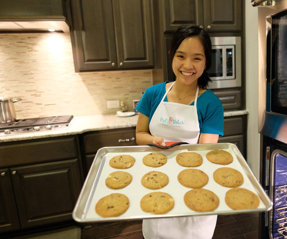 Britney in her Brit’s Batch apron holding a tray of twelve fresh cookies