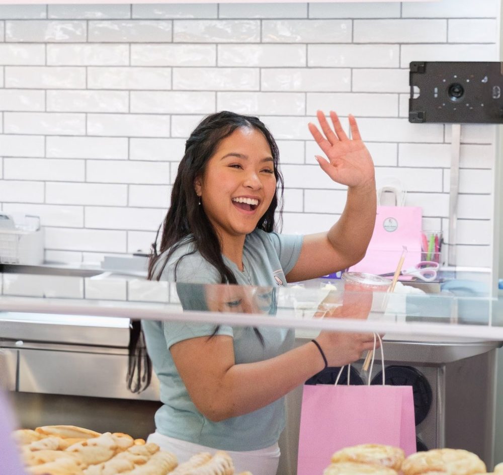 Britney smiling and waving from behind the counter at Brit’s Batch